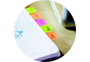 Caderno com marcadores adesivos Post-it coloridos na borda das páginas
